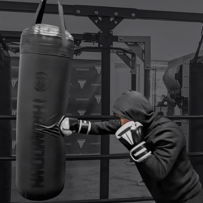 Training on a black Throwdown 4 ft heavy bag with black and white gloves.