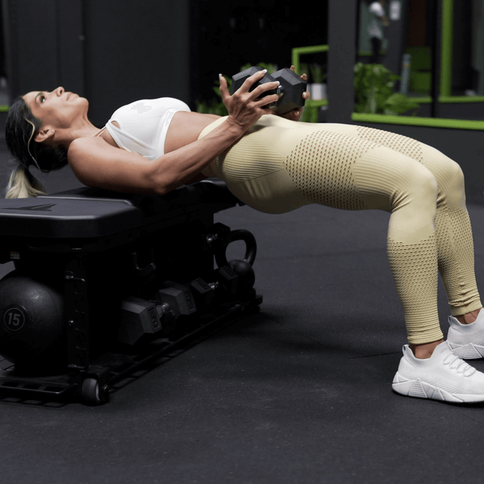 FXD workout bench for studio gym with woman performing hip thrust with dumbbell